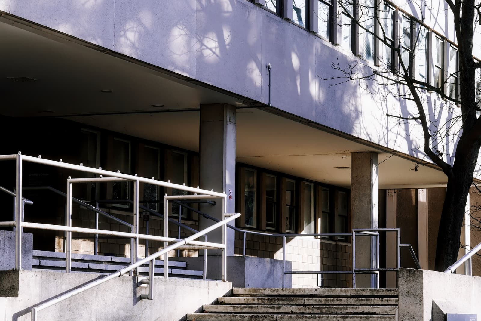 Steps and a railed ramp leading up to a 1960s concrete college building in Oxford