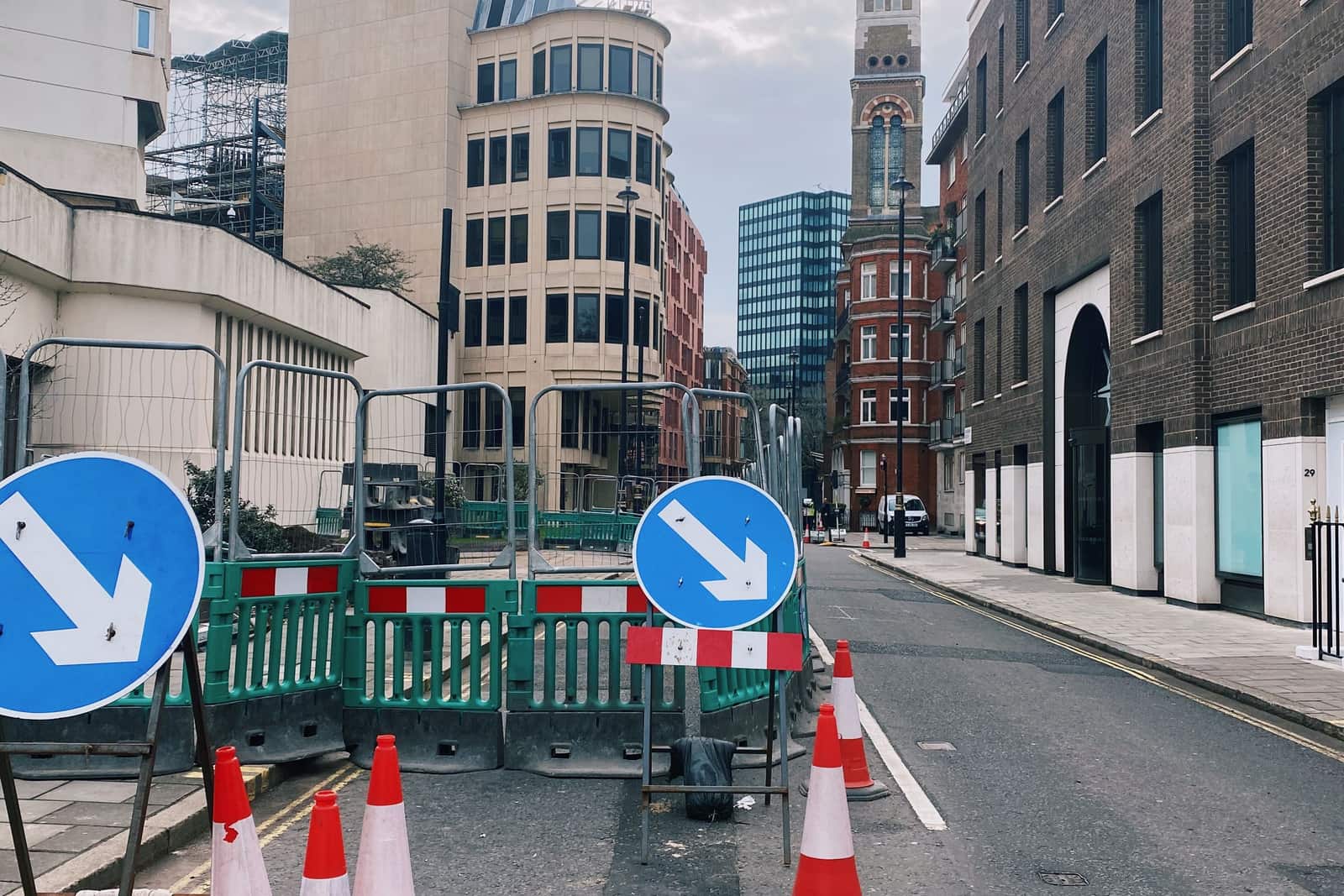 Roadworks on a London street: green barriers, traffic cones and keep-left signs across the carriageway